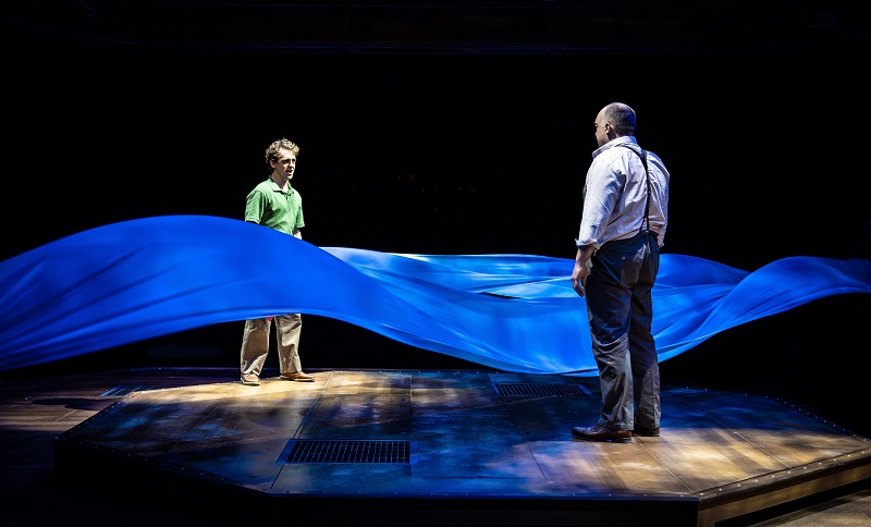 Will Bloom and Edward Bloom standing on either side of the blue ribbon river in Big Fish Marriott Theatre