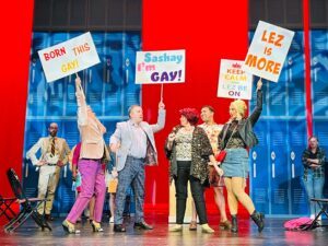 The ensemble of 'The Prom' holding signs at a protest